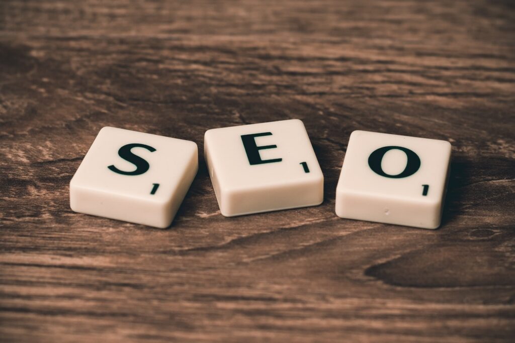 The image shows “SEO” spelled out using letter tiles placed on a wooden surface.