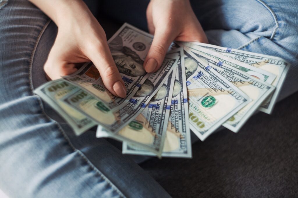 Hands holding and counting US dollar bills.